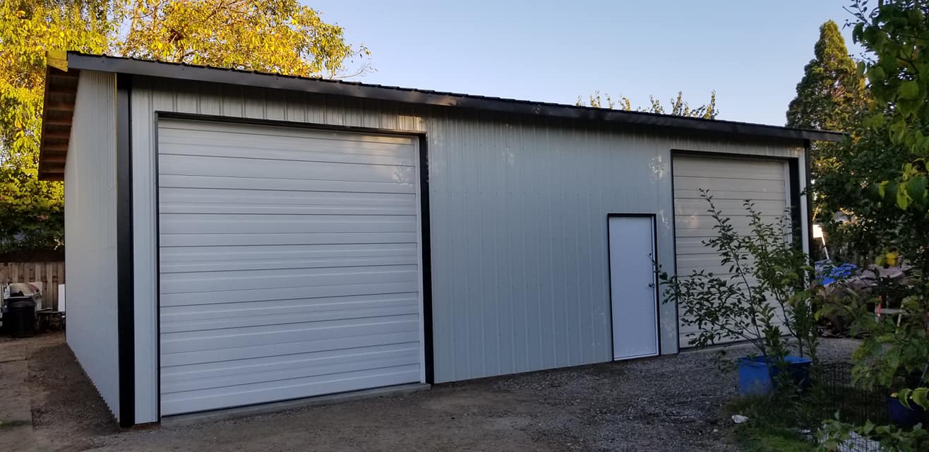 Picture of a very large metal workshop with two overhead doors and a man door.